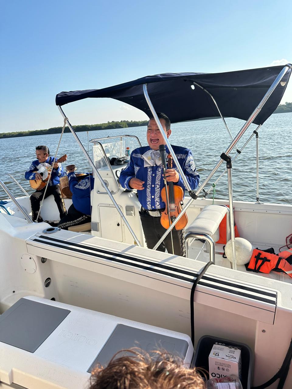 Mariachi tocando el violín a bordo de la lancha durante un paseo por el río