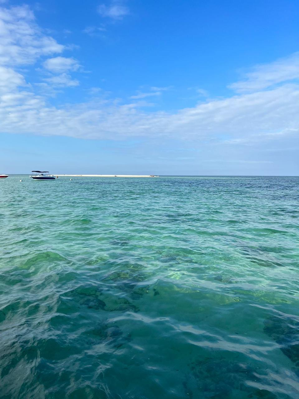 Agua turquesa con banco de arena y lanchas al fondo en el Golfo de México
