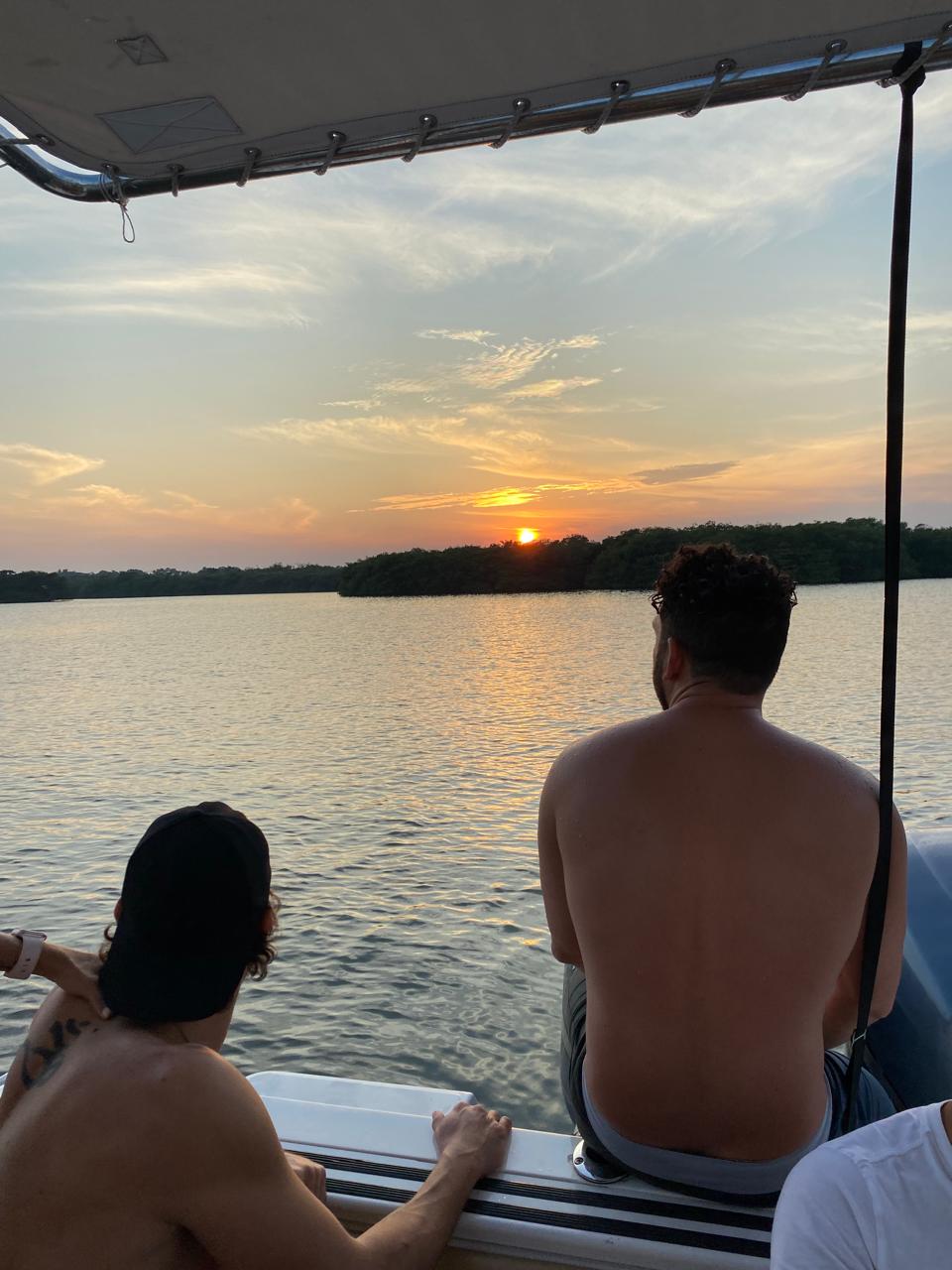 Amigos viendo el atardecer desde la lancha en el río