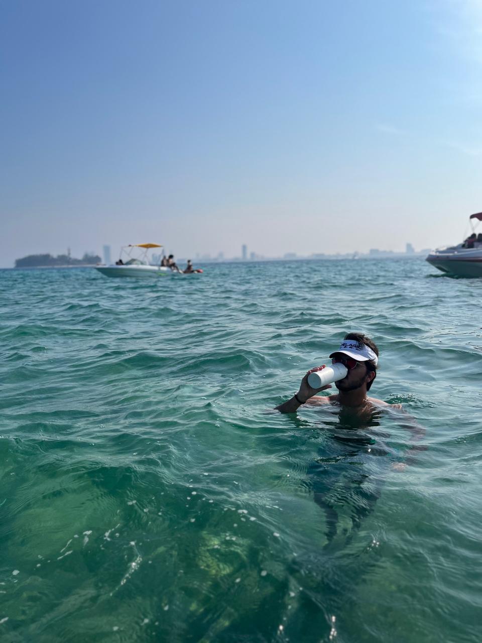 Persona nadando en el mar turquesa junto a las lanchas